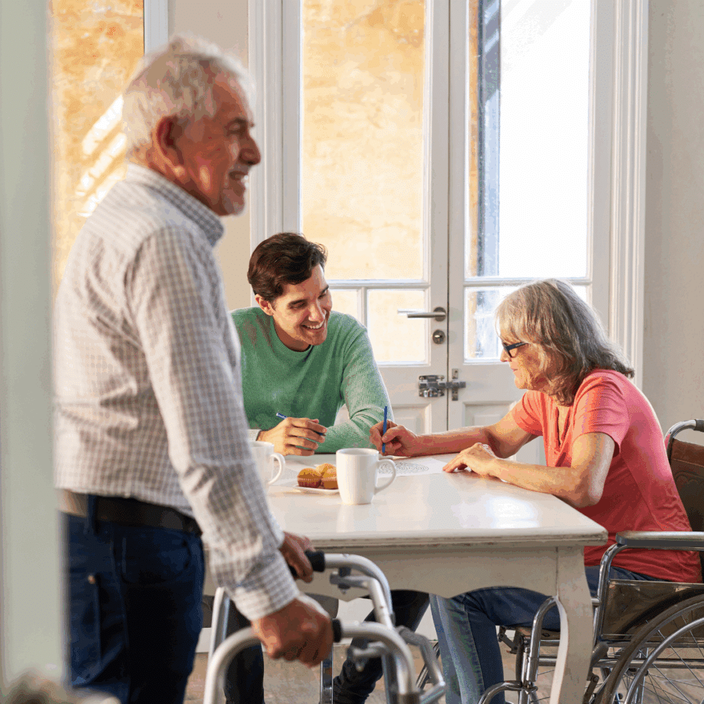 An elderly woman sitting in a wheelchair with a young man and a man standing infornt of them